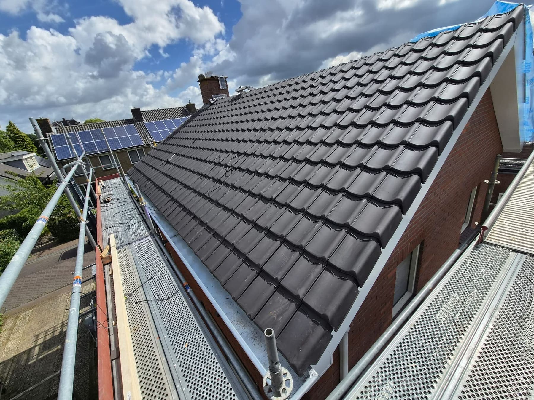 De nieuwe antracietkleurige dakpannen worden gelegd