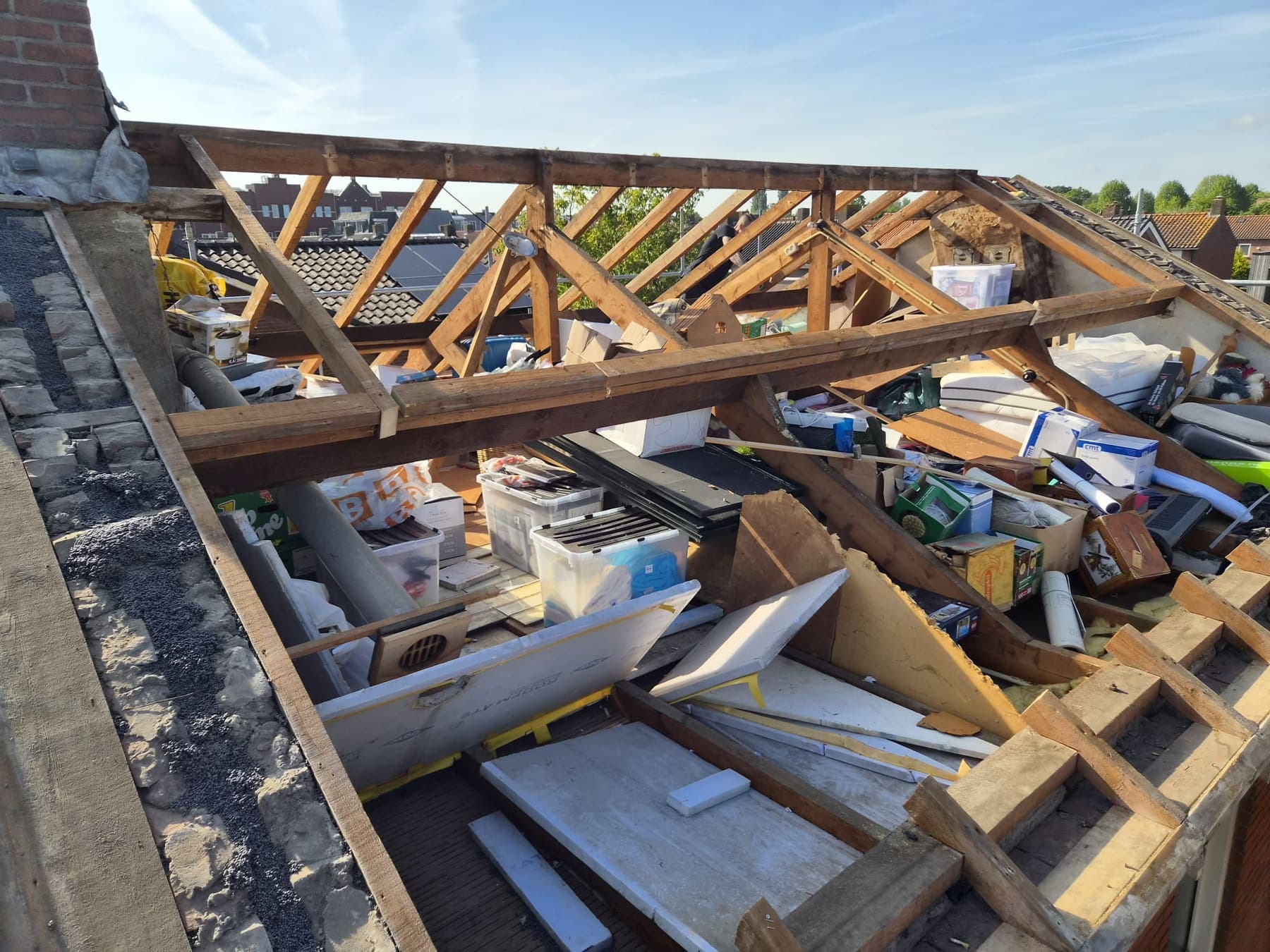 Het dak opengebroken tot op de constructie, oud materiaal wordt afgevoerd