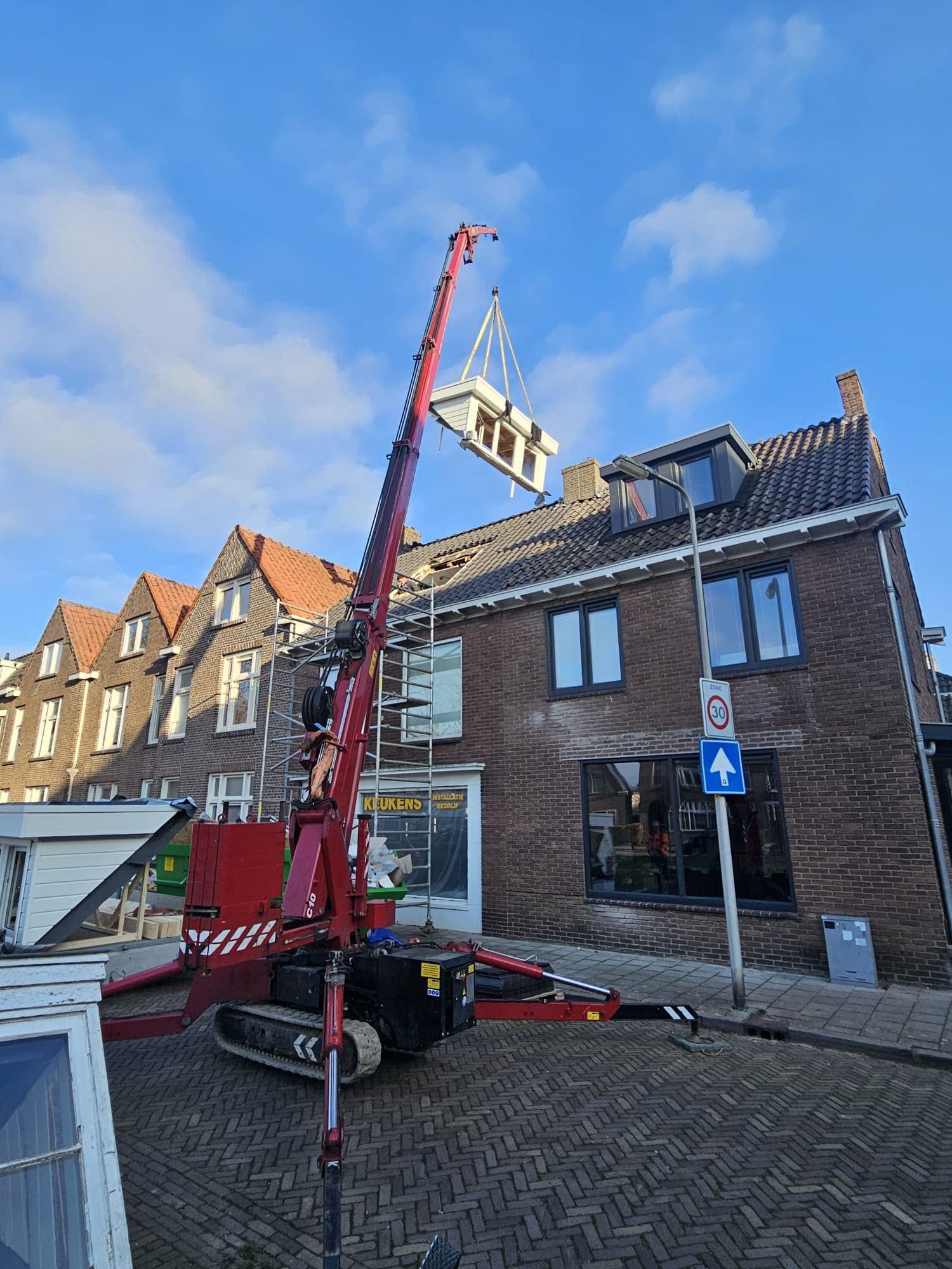 De nieuwe dakkapel wordt met een kraan op het dak gehesen